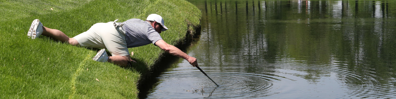 Nach seinem im See versenkten Ball fischender Golfspieler (photo by Ron Alvey / Shutterstock.com)